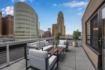 A patio with a table and chairs overlooking a city skyline.